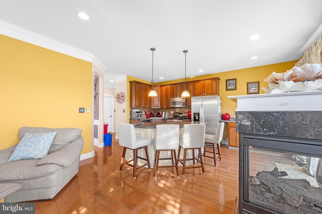 kitchen featuring stainless steel appliances, tasteful backsplash, light hardwood / wood-style flooring, decorative light fixtures, and a breakfast bar area