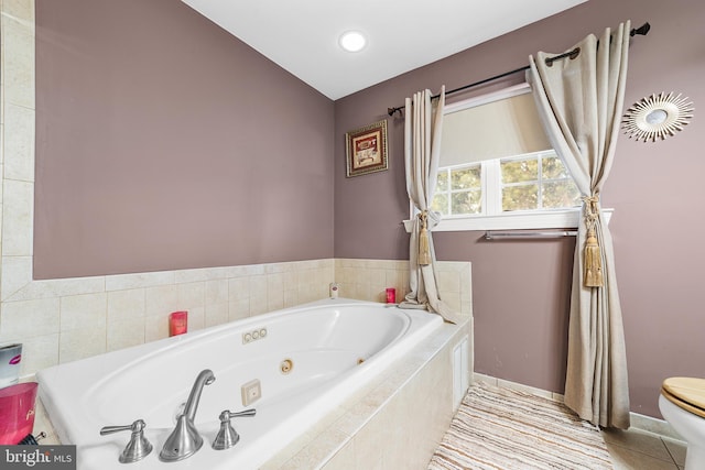 bathroom with tile patterned floors, a relaxing tiled tub, and toilet