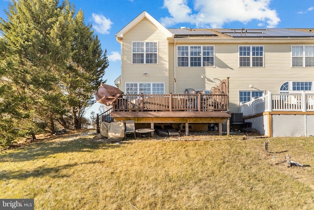 rear view of house featuring solar panels, a yard, central AC, and a wooden deck