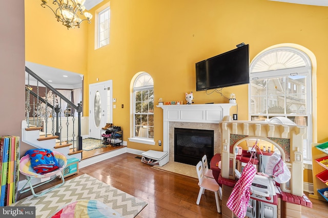 living room featuring hardwood / wood-style floors, a towering ceiling, and an inviting chandelier