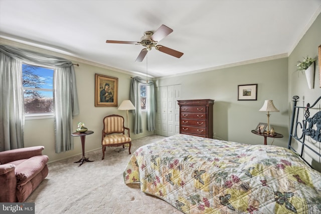 bedroom featuring ceiling fan, a closet, light carpet, and ornamental molding