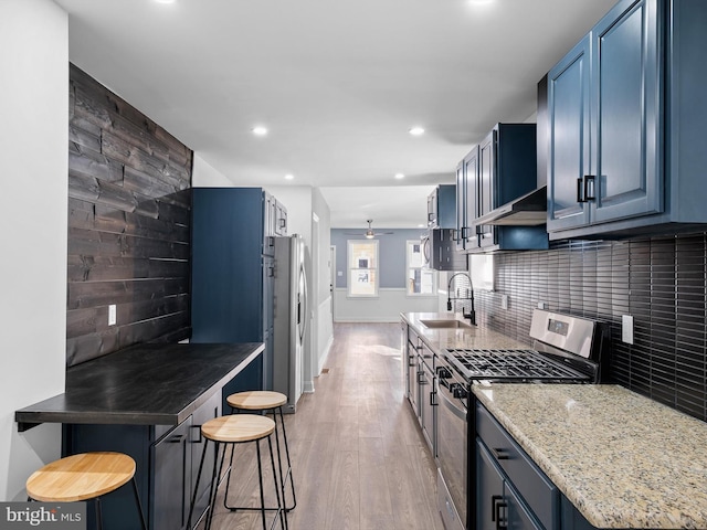 kitchen featuring sink, a kitchen breakfast bar, tasteful backsplash, extractor fan, and appliances with stainless steel finishes