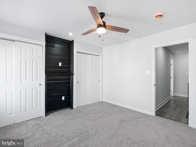 unfurnished bedroom with carpet flooring, ceiling fan, and multiple closets