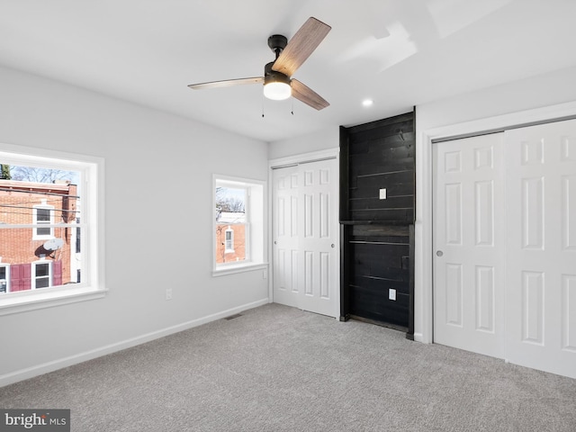 unfurnished bedroom with ceiling fan, light carpet, and multiple windows