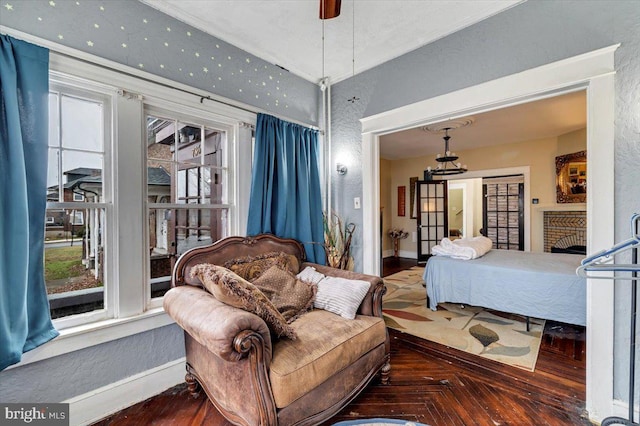 bedroom featuring ceiling fan, parquet flooring, a fireplace, and multiple windows