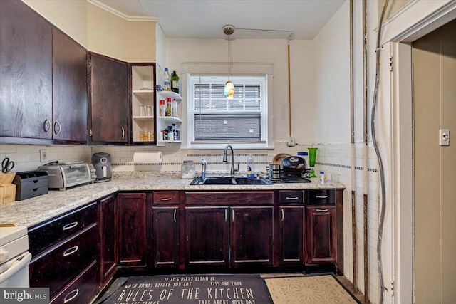 kitchen featuring pendant lighting, light stone countertops, sink, and tasteful backsplash