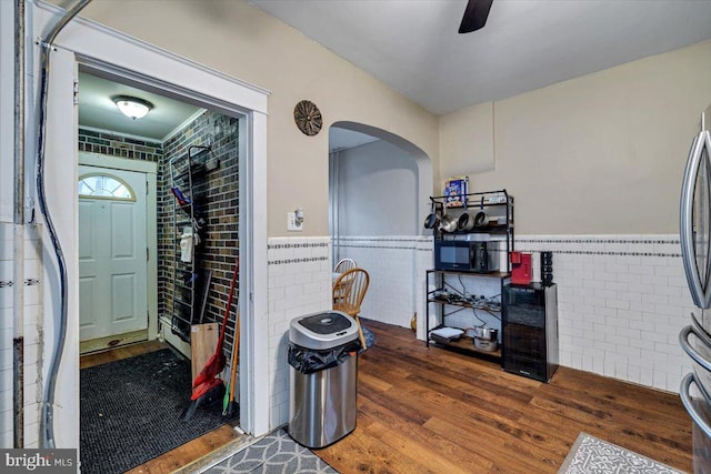 interior space with dark hardwood / wood-style floors, tile walls, and ceiling fan