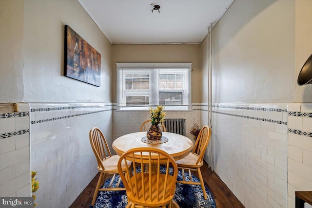 dining space featuring radiator, dark hardwood / wood-style flooring, and tile walls