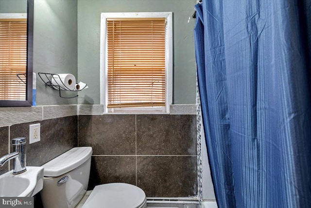 bathroom with walk in shower, sink, tile walls, and toilet