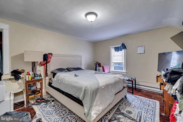 bedroom with a textured ceiling, hardwood / wood-style flooring, and baseboard heating