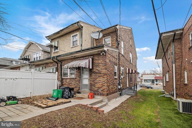 back of house with central AC unit and a lawn