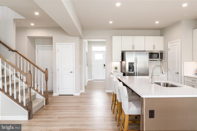 kitchen featuring sink, a kitchen island with sink, stainless steel appliances, decorative backsplash, and white cabinets