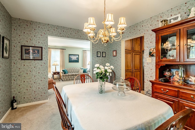 dining space with light carpet and a notable chandelier