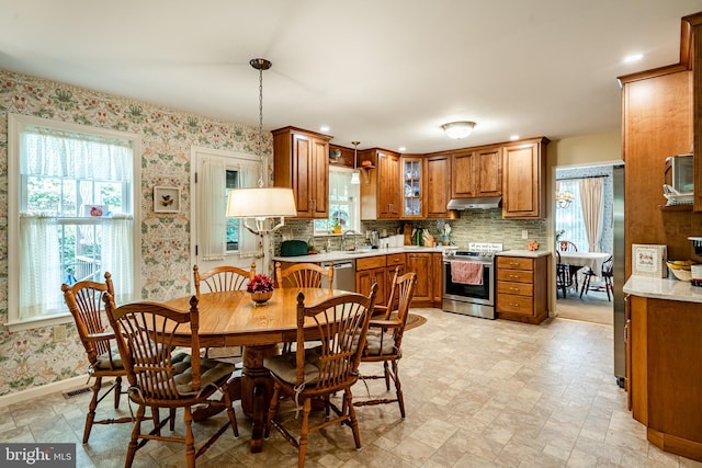 kitchen with hanging light fixtures, decorative backsplash, sink, and appliances with stainless steel finishes