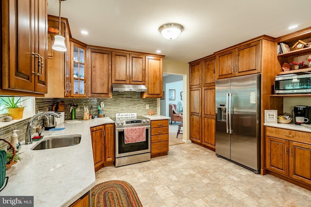 kitchen with appliances with stainless steel finishes, tasteful backsplash, sink, hanging light fixtures, and light stone counters