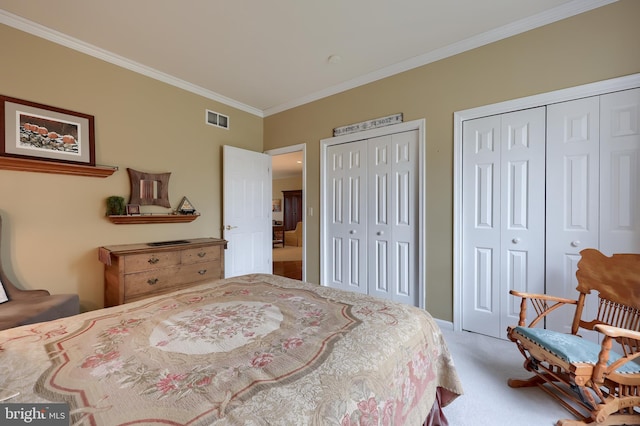 bedroom featuring carpet flooring, crown molding, and two closets