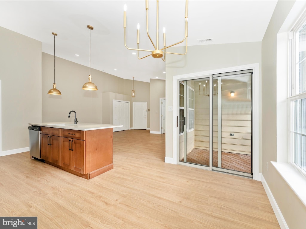 kitchen with sink, dishwasher, hanging light fixtures, a notable chandelier, and a kitchen island with sink