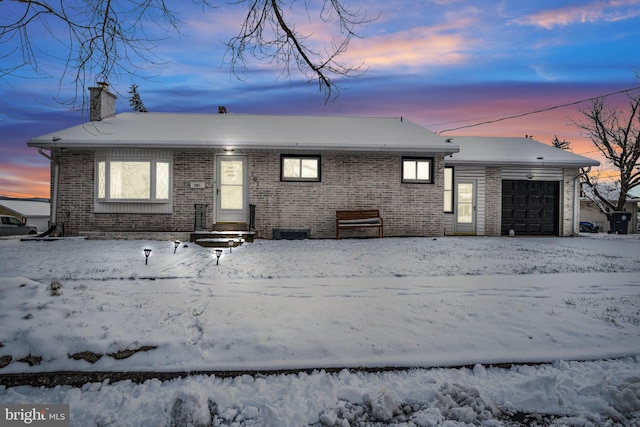 snow covered rear of property with a garage