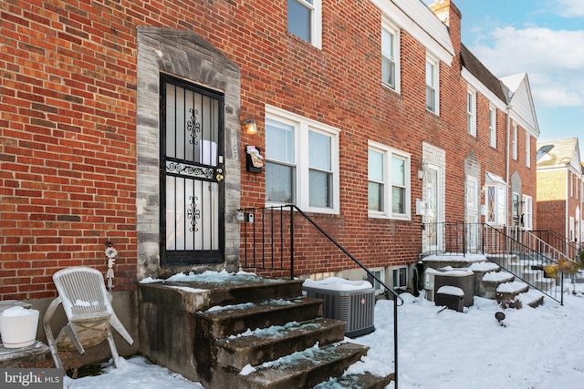 snow covered property entrance with central AC