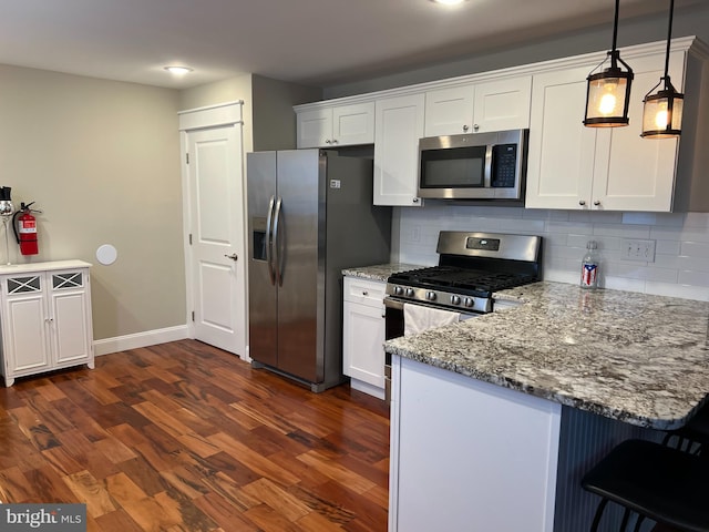 kitchen featuring dark hardwood / wood-style flooring, white cabinetry, hanging light fixtures, and appliances with stainless steel finishes