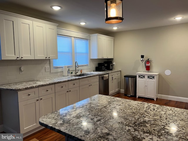 kitchen with stainless steel dishwasher, decorative backsplash, white cabinetry, and sink