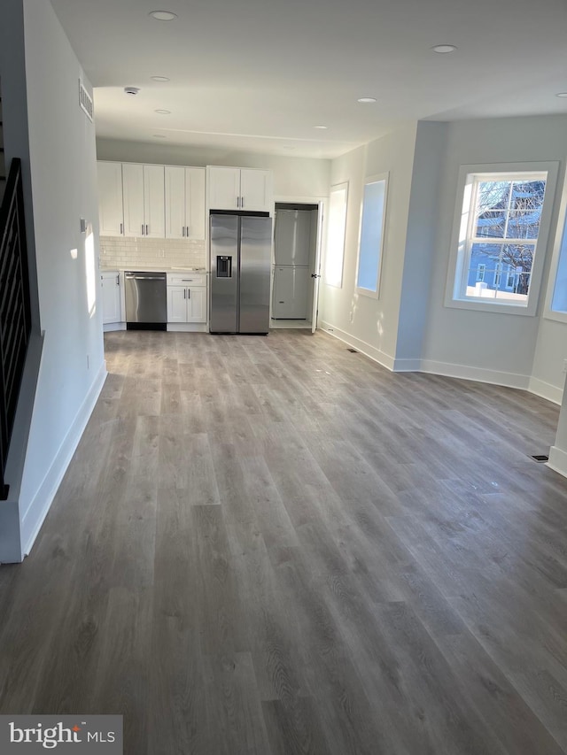 kitchen with backsplash, white cabinetry, stainless steel appliances, and wood-type flooring