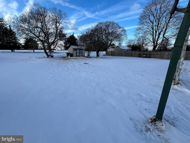 yard layered in snow featuring a storage unit