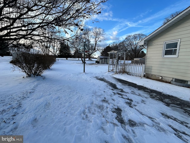 yard covered in snow with a storage shed