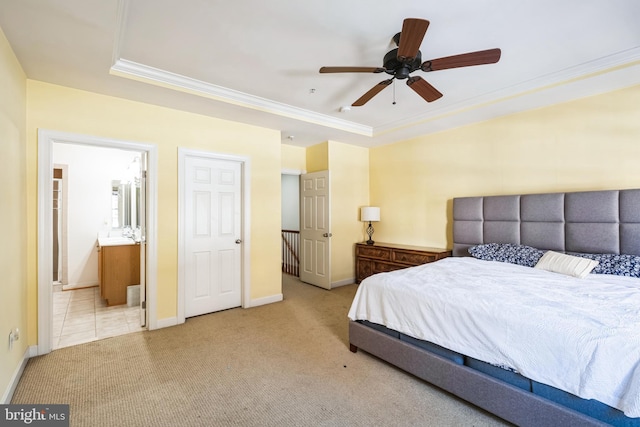 bedroom featuring ensuite bathroom, crown molding, light colored carpet, ceiling fan, and a tray ceiling