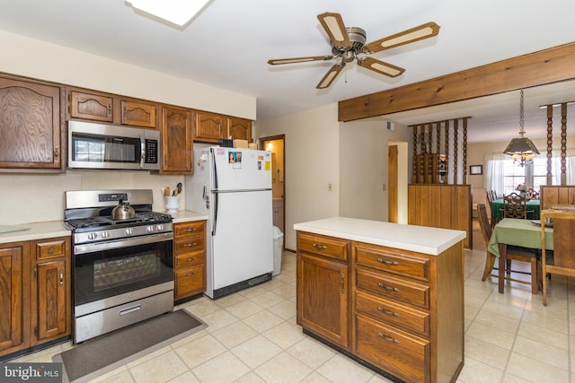 kitchen featuring ceiling fan, hanging light fixtures, a kitchen island, and stainless steel appliances