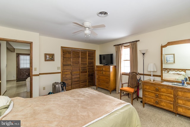 bedroom with ceiling fan, a closet, and light carpet