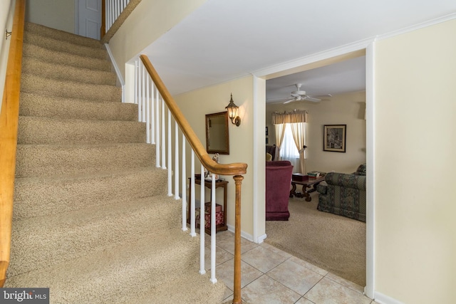 stairs with tile patterned flooring, ceiling fan, and crown molding