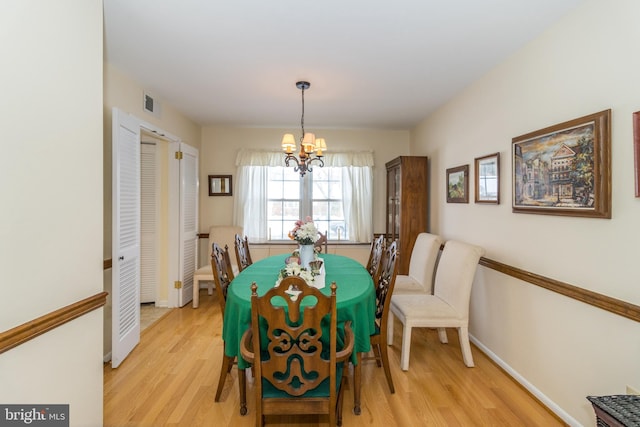 dining space with light wood-type flooring and a notable chandelier