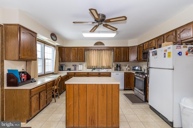 kitchen featuring ceiling fan, sink, light tile patterned flooring, a kitchen island, and appliances with stainless steel finishes