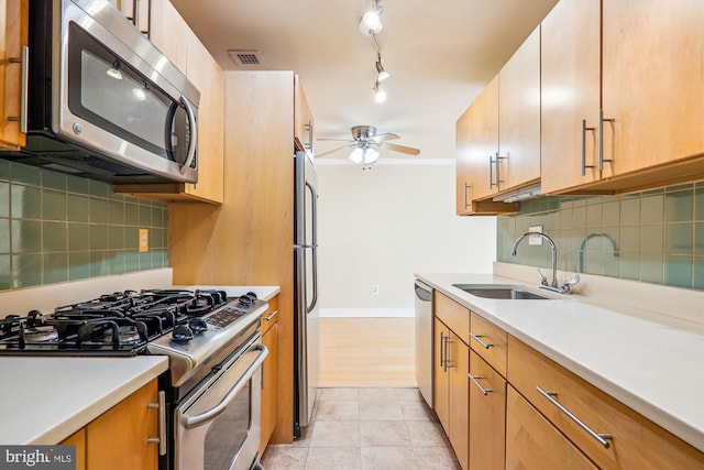 kitchen featuring stainless steel appliances, light tile patterned floors, ceiling fan, decorative backsplash, and sink