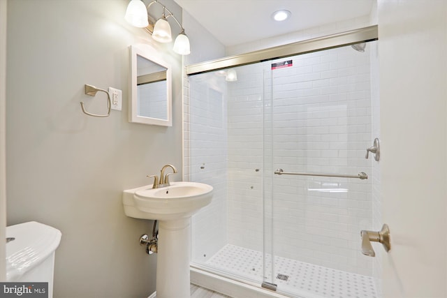 bathroom featuring toilet and a shower with shower door