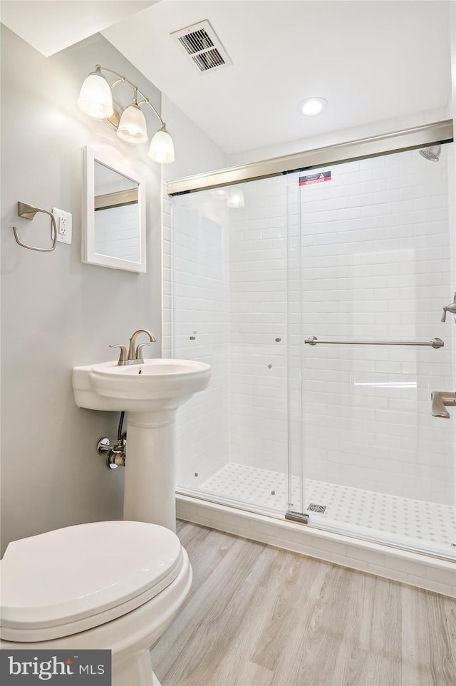 bathroom featuring toilet, hardwood / wood-style flooring, and walk in shower