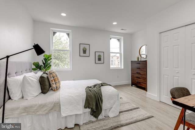 bedroom featuring a closet, multiple windows, and light hardwood / wood-style floors