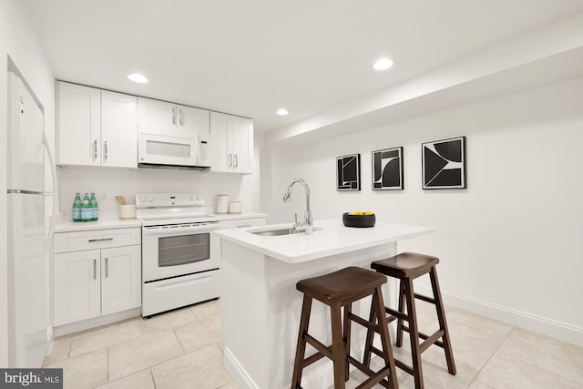 kitchen featuring white appliances, sink, light tile patterned floors, white cabinetry, and an island with sink