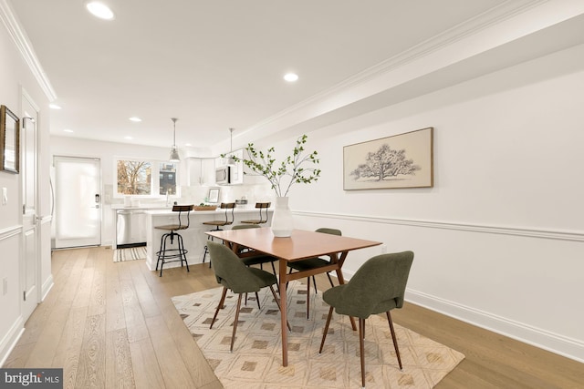 dining room featuring light wood-type flooring and crown molding