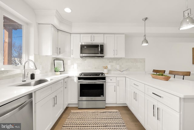 kitchen with white cabinets, sink, decorative backsplash, appliances with stainless steel finishes, and decorative light fixtures