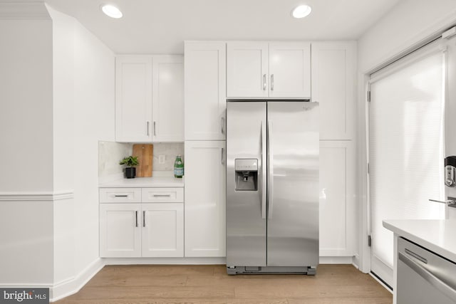 kitchen featuring white cabinets, tasteful backsplash, stainless steel appliances, and light hardwood / wood-style flooring