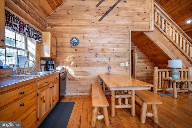 kitchen with sink, wooden ceiling, black dishwasher, wood walls, and light hardwood / wood-style floors