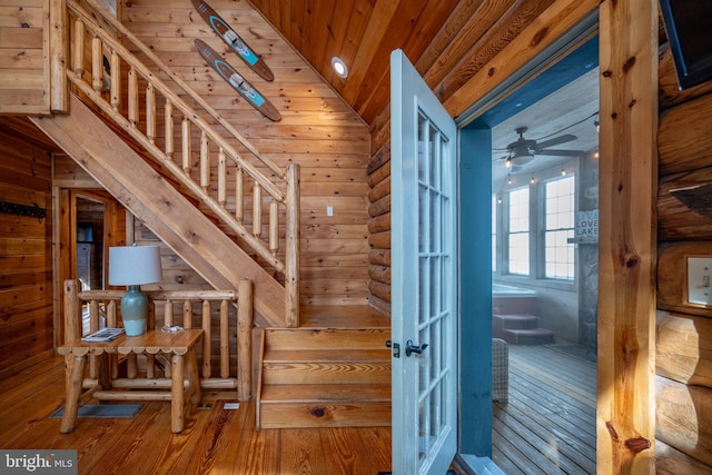 stairway featuring hardwood / wood-style floors, wood walls, vaulted ceiling, ceiling fan, and wooden ceiling