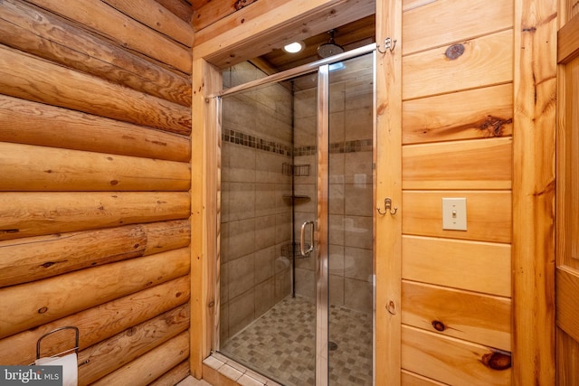 bathroom featuring a shower with door and log walls