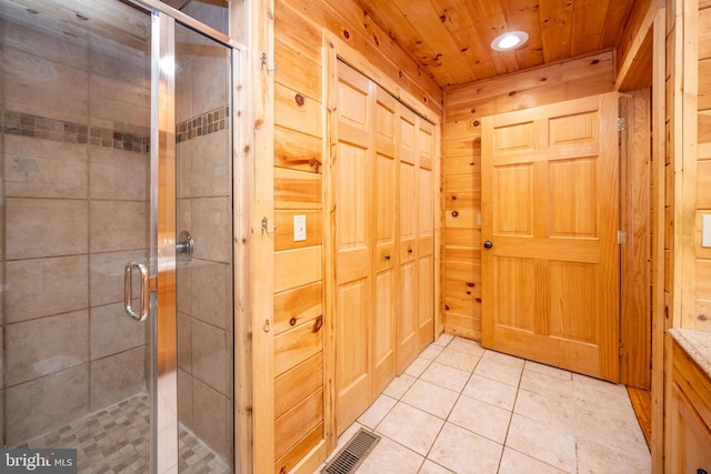 bathroom with wood ceiling, a shower with shower door, wood walls, and tile patterned flooring