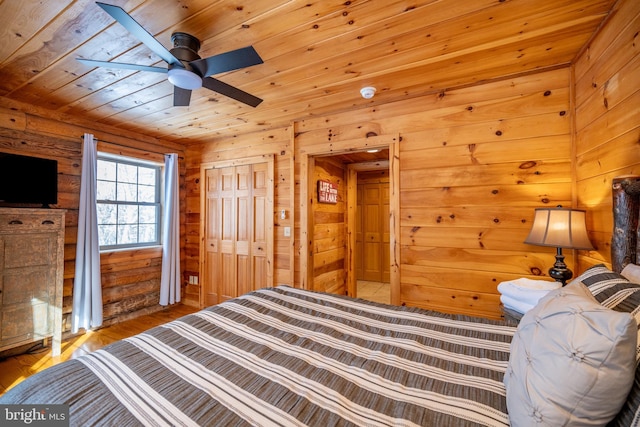 bedroom with ceiling fan, wood walls, and wooden ceiling