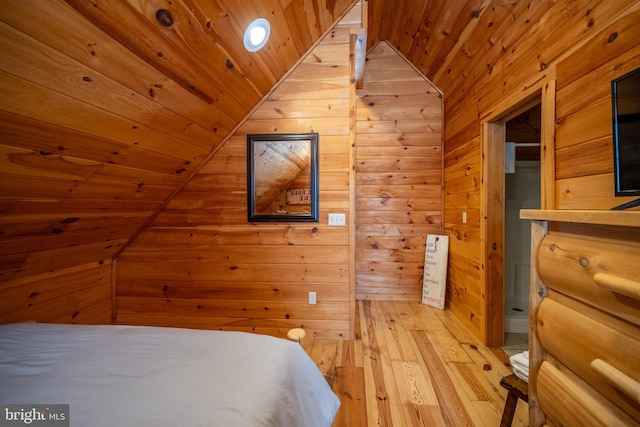 unfurnished bedroom featuring wooden ceiling, vaulted ceiling, wood walls, and light wood-type flooring