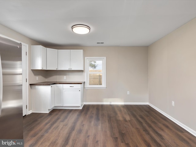 kitchen featuring stainless steel refrigerator, dark hardwood / wood-style floors, and white cabinets