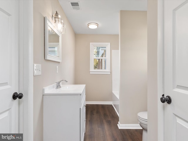 bathroom featuring vanity, hardwood / wood-style floors, a bath, and toilet